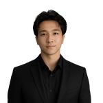 Jayden Nguyen, Associate Software Engineer at Leidos QTC Health Services, looks at the camera in a professional headshot wearing a black blazer over a black collared shirt against a clean, plain background.