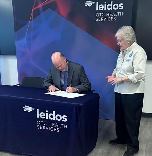 Person signing document with onlooker