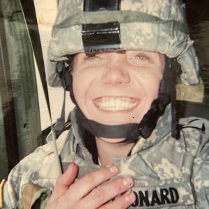 Woman in army camo uniform smiles 