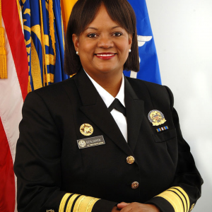 Photo of woman in uniform smiling in front of American flag