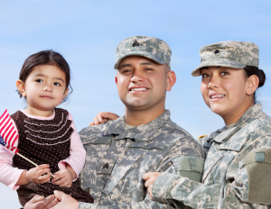 Little girl holding American flag with a man and woman wearing military outfits
